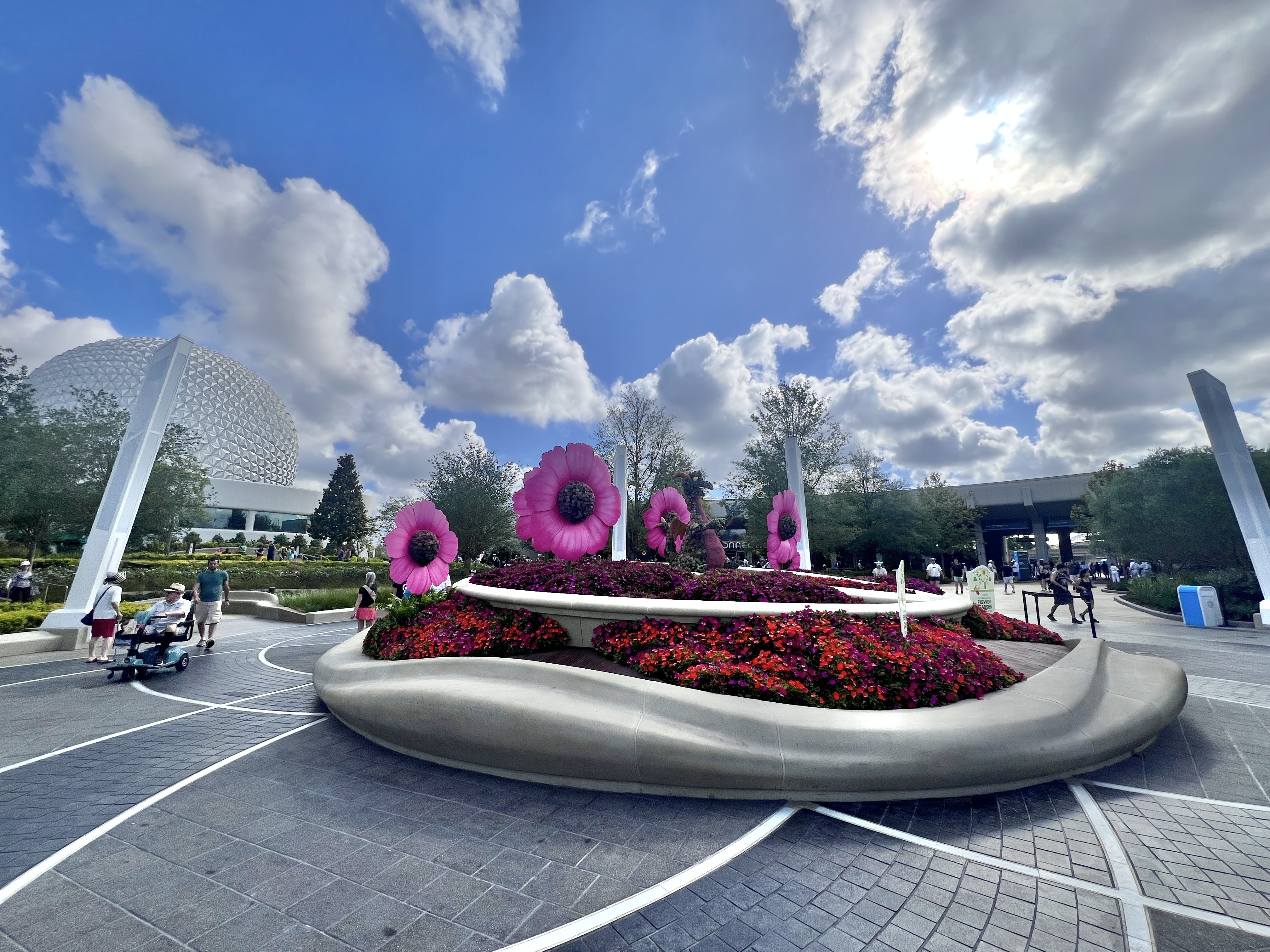Spaceship Earth and the EPCOT entrance during Flower and Garden Festival, with giant flower sculptures and guests walking on a spring afternoon.