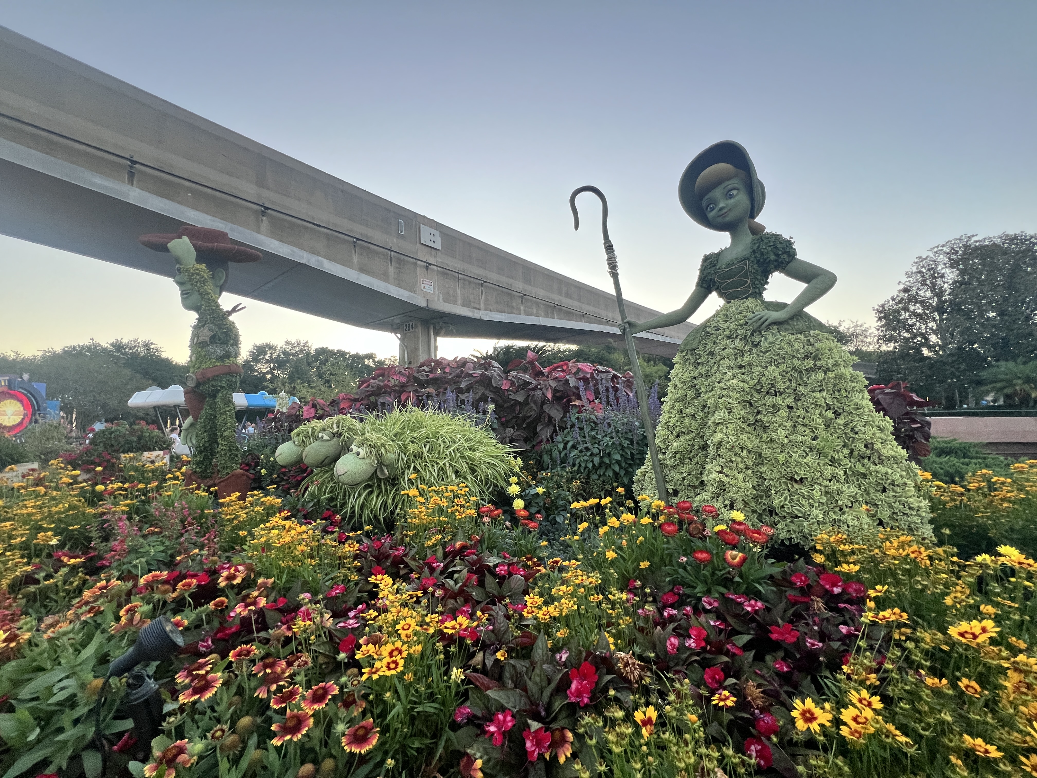 Bo Peep topiary surrounded by wildflowers with the EPCOT monorail overhead during the Flower and Garden Festival