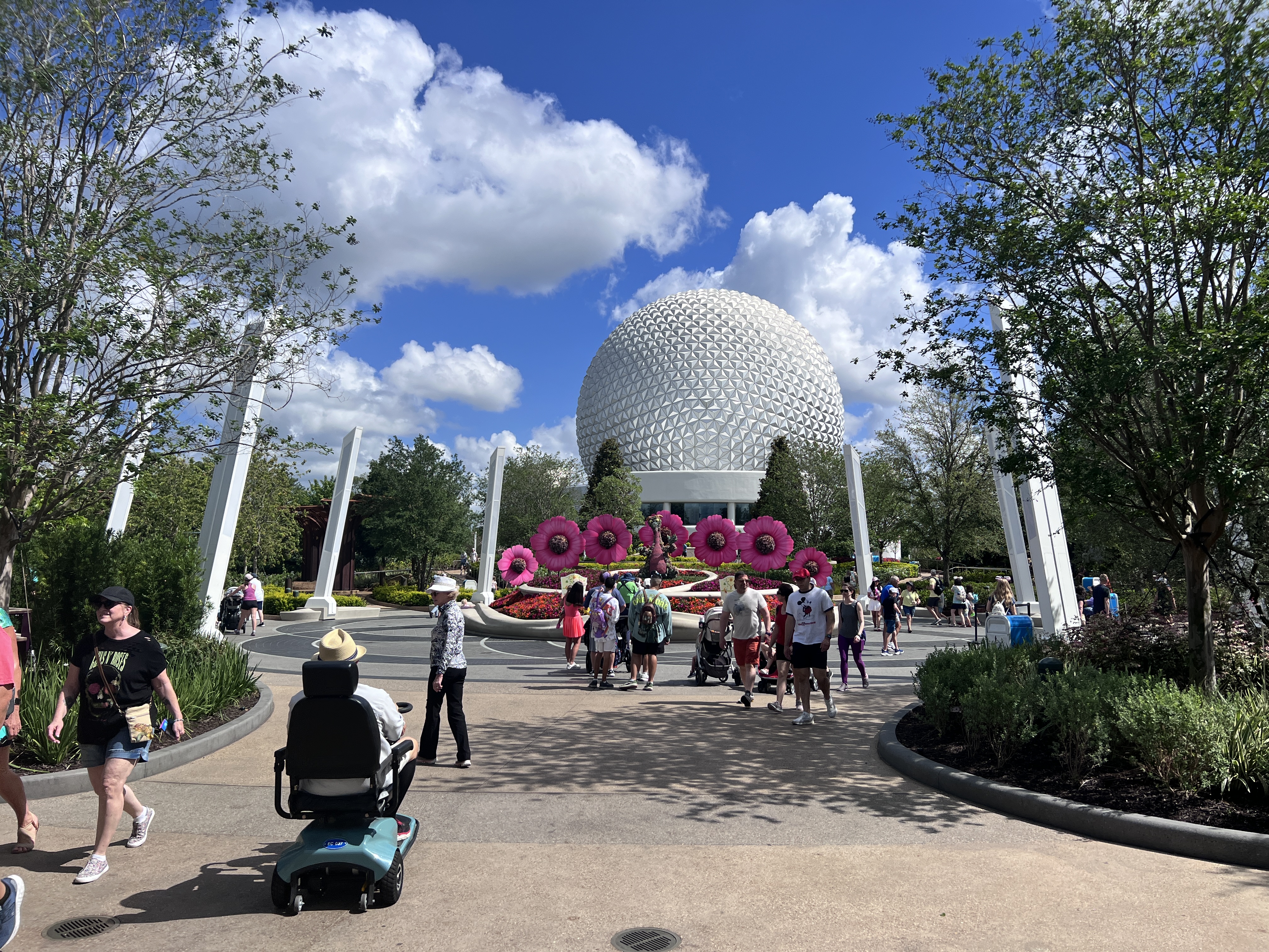 Spaceship Earth at EPCOT framed by pink flower sculptures and spring crowds during the Flower and Garden Festival
