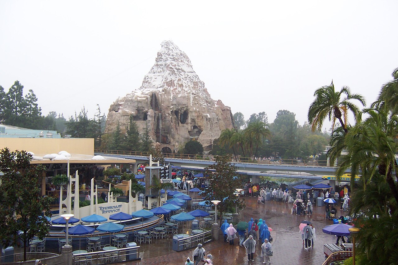 The Matterhorn rising above Tomorrowland at Disneyland, guests walking below on a gray morning